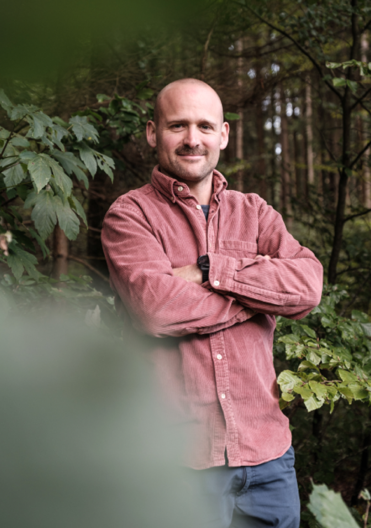 Manuel Seiler, Inhaber von via.natur, mit verschränkten Armen im Wald